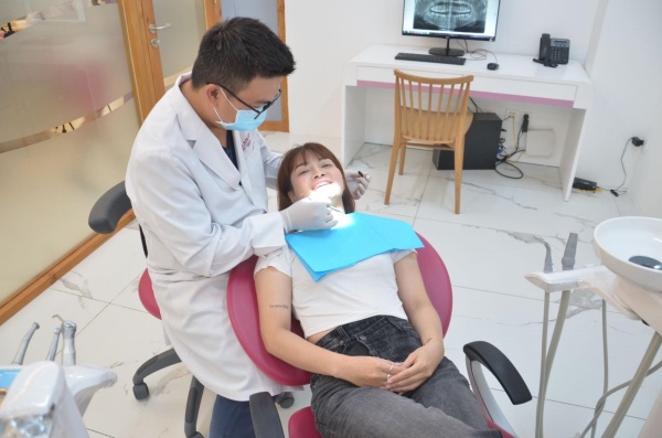 Hình ảnh bác sĩ tại Elite Dental thăm khám và nhổ răng khôn bị sâu cho khách hàng